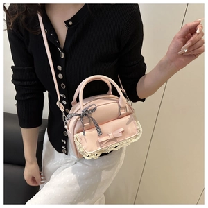 Close-up of pink PU leather handbag with lace trim, bow detail, and checkered ribbon scarf