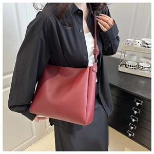 Detail view of large dark red leather tote bag worn by model in minimalist office setting