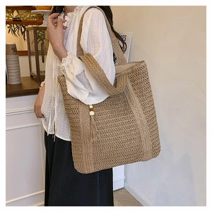 Close-up of a woven straw tote bag with long tassels and wooden beads detail