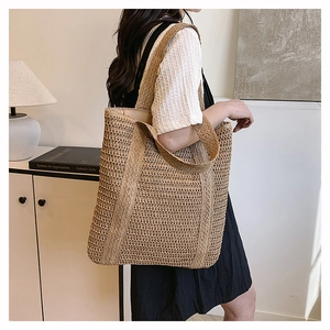 Detail of hand-woven straw tote bag showing natural texture and sturdy shoulder straps