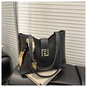 Detail of black leather tote bag featuring contrast stitching and a gold geometric clasp