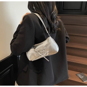 Close-up of a silver shoulder bag with unique corset-style lace-up detailing and texture