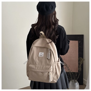 Detail of beige Japanese style backpack with smiley face patch and woven zippers