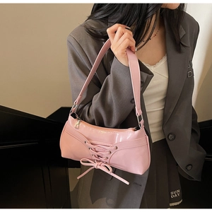 Detail of pink bow-knot shoulder bag featuring corset-style lace-up design and matte finish