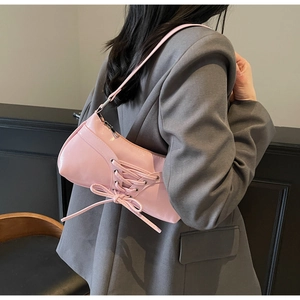 Pink glossy shoulder bag with bow detailing worn over a grey blazer for a Y2K aesthetic
