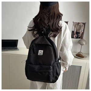 Rear view of black student backpack with smiling face patch on a cozy desk background