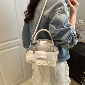 Beige shell bag with lace trim and bow charm worn with casual denim and lace dress