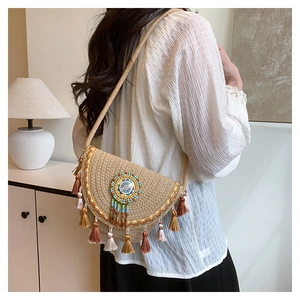 Detail of woven straw crossbody bag featuring colorful tassels and beadwork embroidery