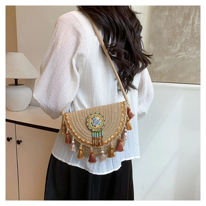 Detail of bohemian straw crossbody bag featuring colorful beadwork and tiered fringe tassels