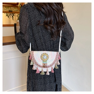 Detail of bohemian woven crossbody bag with colorful embroidery and tassel accents