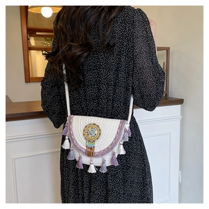 Detail of bohemian straw crossbody bag featuring colorful beads and long purple tassels