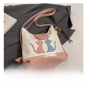 Détail d'un sac cabas bicolore avec contours de chat et breloque en corde tressée