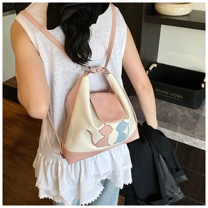 Détail du sac à dos en cuir verni rose et blanc avec broderie chat et texture brillante