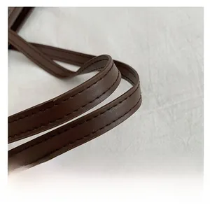 Detail of brown PU leather tote handle featuring refined stitching and pebble texture