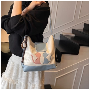 Détail du cabas en cuir blanc et bleu avec broderie chat et pendentif de baseball