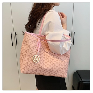 Close-up of pink tote bag with 'M' letter print and gold circular metal charm detail