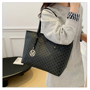Détail du cabas noir avec motif monogramme, pendentif doré M et texture en cuir raffiné