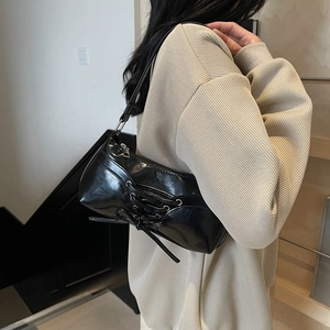 Glossy black corset-style underarm bag with decorative crossover lace-up design