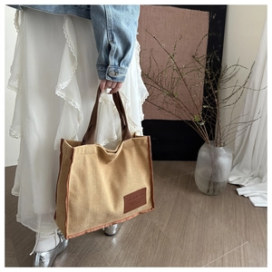 Close-up of canvas tote bag with fashion leather tag and brown contrast stitching