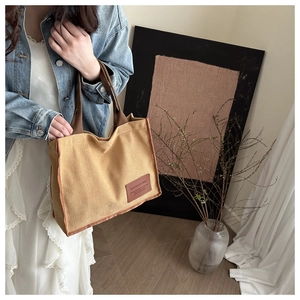 Close-up of khaki corduroy tote bag featuring a leather patch and brown fabric handle