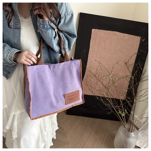 Purple corduroy tote bag with brown webbing handles and leather fashion label detail