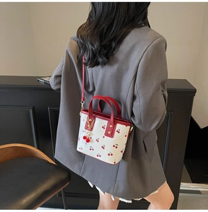Detail of cherry pattern bucket bag with red metal pendant and adjustable strap