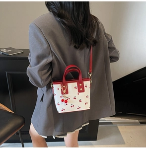 Detail of cherry print tote bag with 3D cherry charm worn on a grey blazer outfit