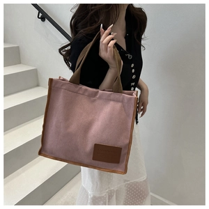 Detail of pink corduroy tote bag featuring brown trim and fashionable shoulder strap