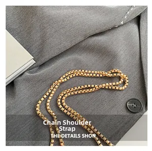 Detail of the high-shine gold box chain strap on a trendy saddle bag surface