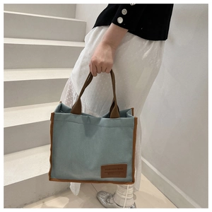 Detail of blue waffle pattern tote bag with brown leather contrast handle and trim