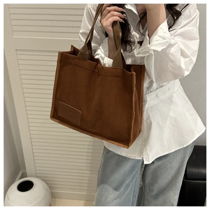 Close-up of brown corduroy tote bag with textured stripes and decorative leather patch