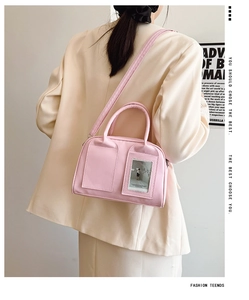 Close-up of pink shell bag with dual pockets, transparent card slot and slim shoulder strap