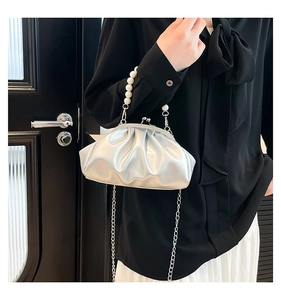 Detail of silver ruched cloud bag featuring elegant pearl handle and metal chain strap
