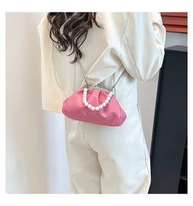 Detail of vibrant pink pleated dumpling bag with pearl handle and silver chain strap