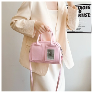 Detailed shot of pink shell bag with card slot, worn with beige blazer against white wall