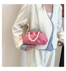 Close-up of pink cloud clutch bag with pearl handle and metal chain on white blazer