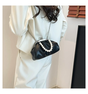Detail of black pleated cloud bag with pearl handle and metal chain on white suit