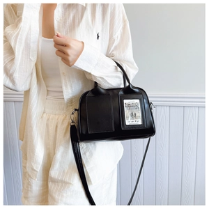 Detail of a black crossbody bag showing decorative front pockets and silver hardware