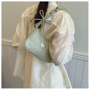 Detail of light green ruched shoulder bag featuring silver butterfly and bow strap