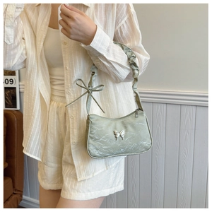 Detail of light green ruched shoulder bag featuring silver butterfly buckle and bow strap