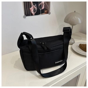 Detailed view of the black nylon crossbody bag featuring a fashion label and wide strap