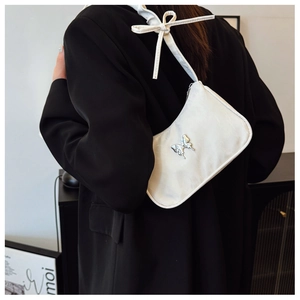 Detail of white hobo bag with silver butterfly charm and bow strap on model