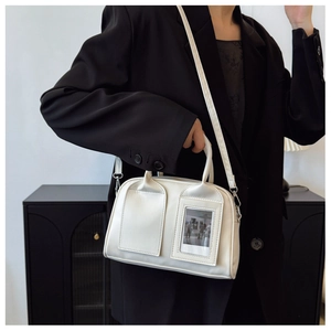 Close-up of white leather shell bag with photo slot and strap shown on model in studio