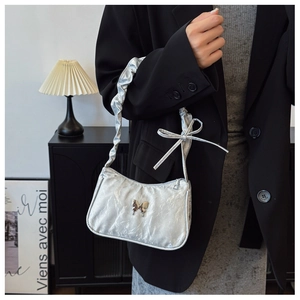 Detail of silver metallic hobo bag with pleated strap and metallic butterfly charm