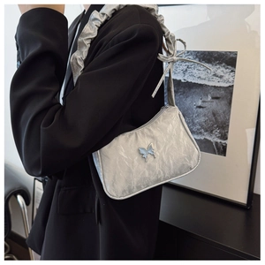 Detail of silver metallic textured baguette bag featuring metal butterfly logo and ruffles