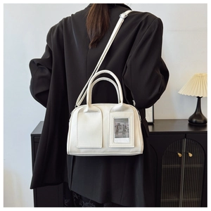 Detail of white leather shell bag with adjustable strap and transparent photo pocket