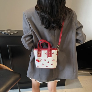 White bucket bag with cherry print and red handles for women's crossbody wear
