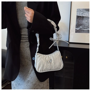 Detail of silver metallic hobo bag featuring butterfly ornament and ruffled strap