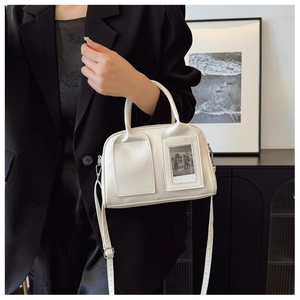 Detail of white shell handbag with card slot and adjustable shoulder strap on black suit
