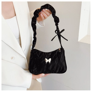 Detail of black pleated baguette bag with silver butterfly buckle and ruffled strap
